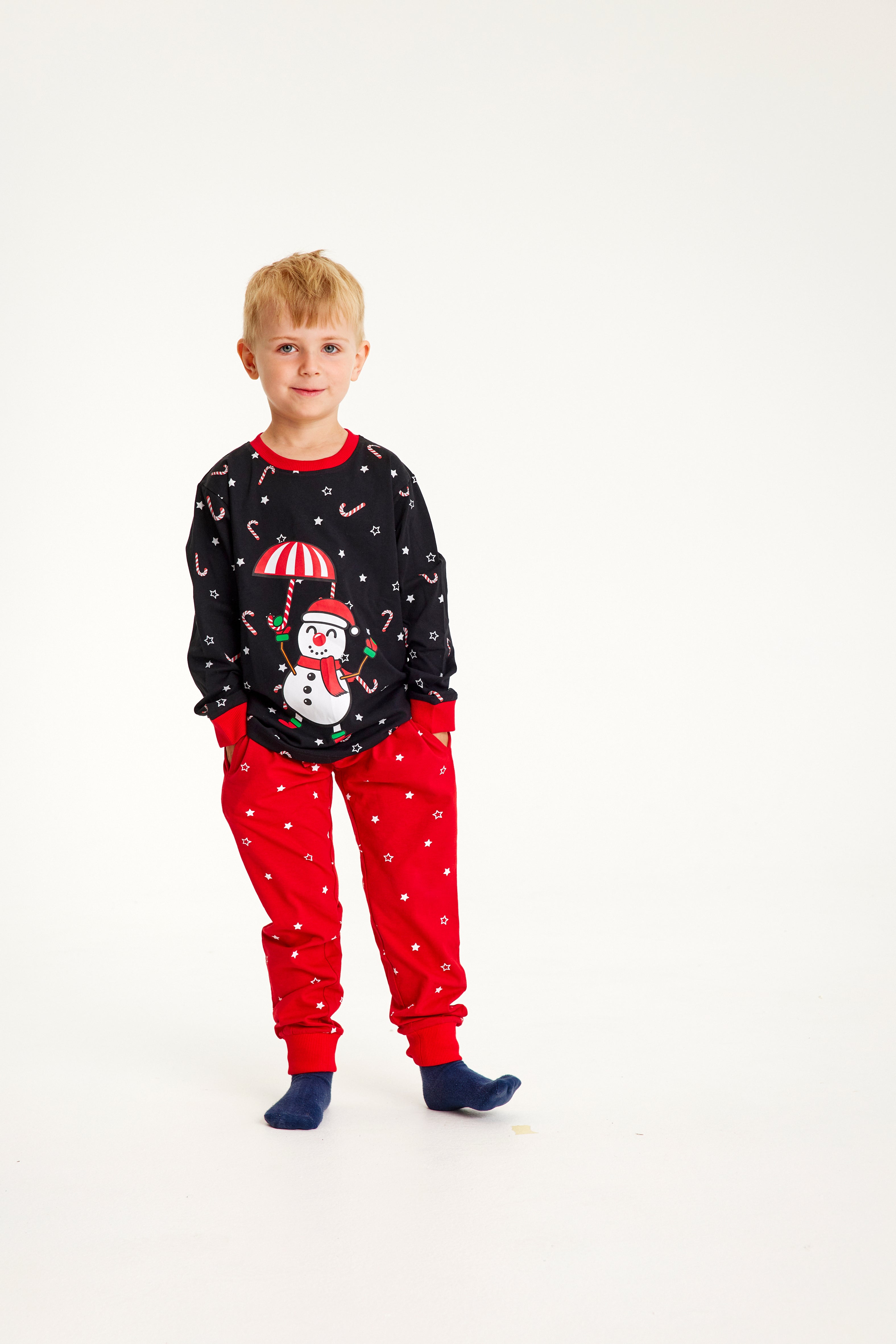 En lille dreng iført røde bukser og en sort pyjamasoverdel.